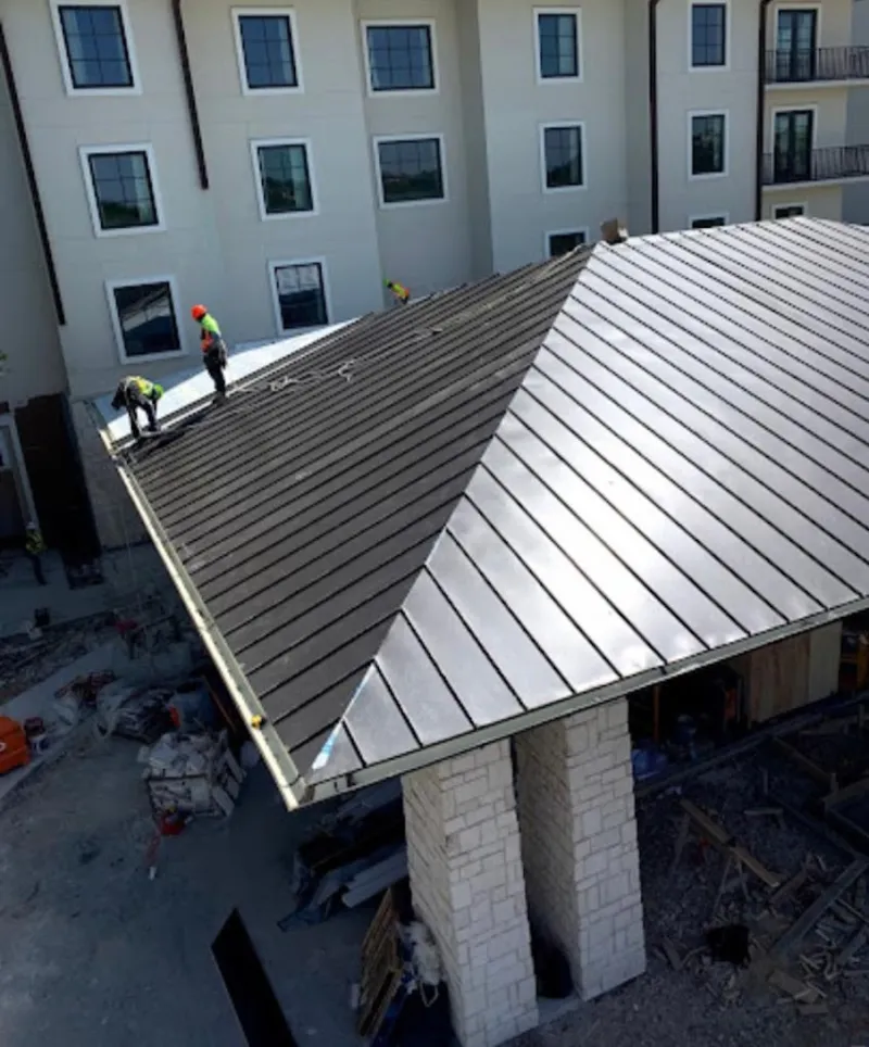 Crew installing standing seam metal roof panels on a commercial project in Sandy Springs